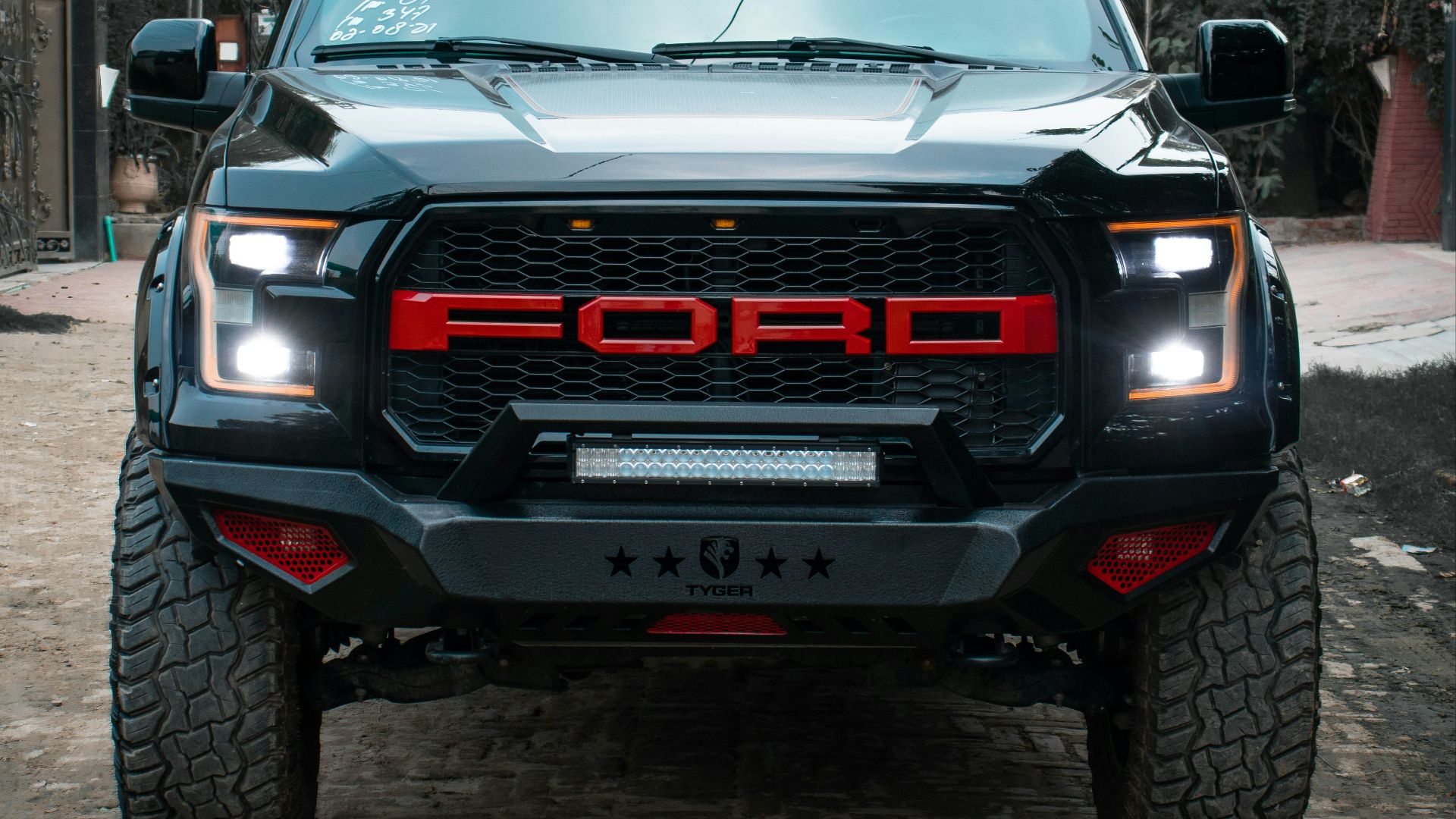 the front of a black truck parked on a cobblestone street