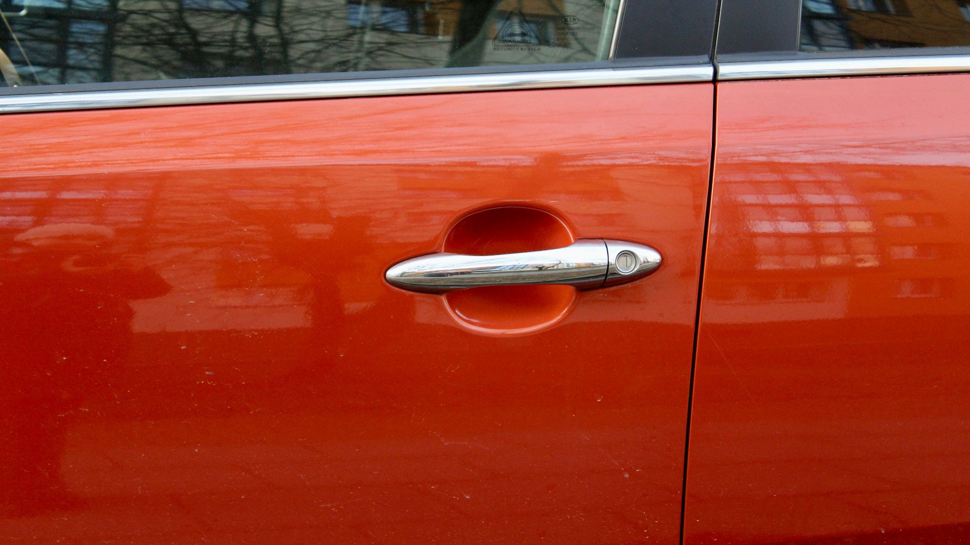 An orange car door with a silver handle.