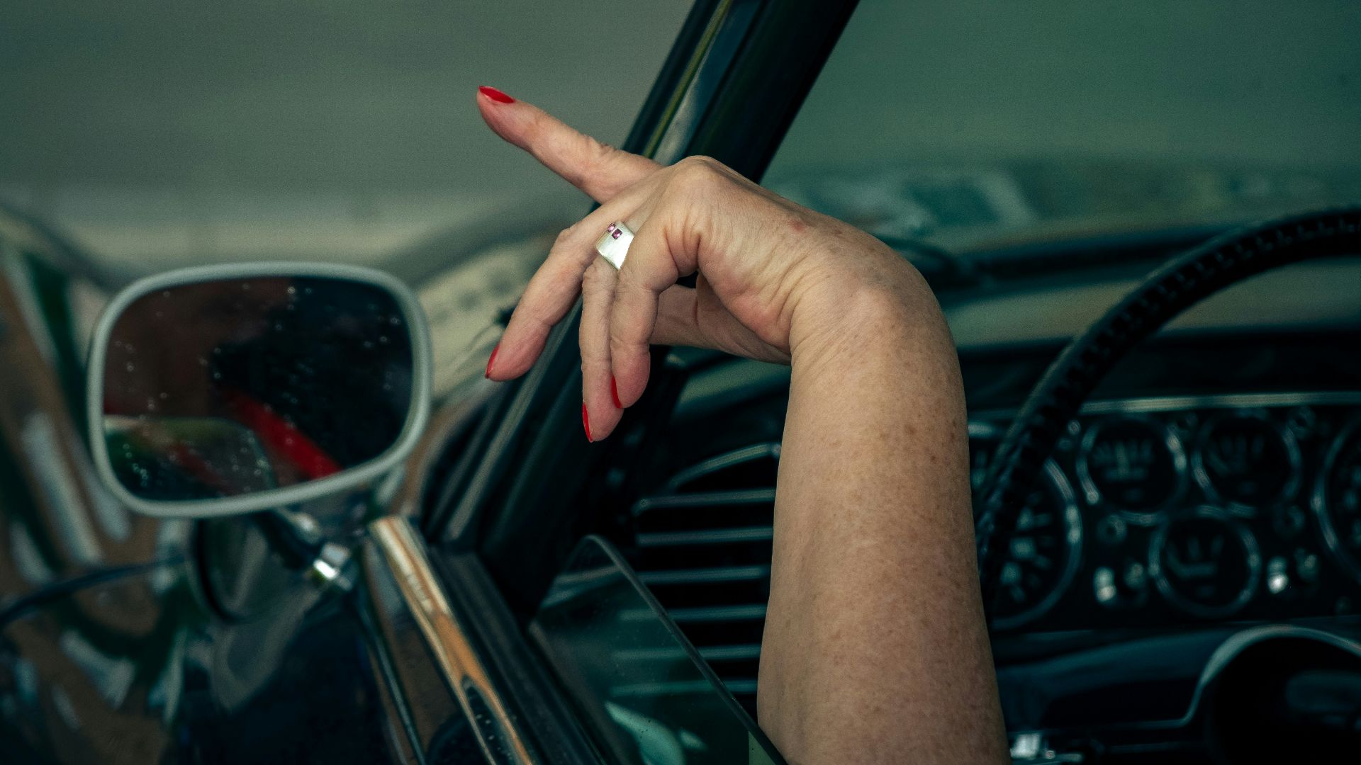 person inside the car pointing on outdoor during daytime