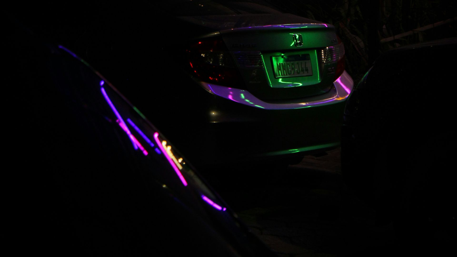 a car is parked in the dark with neon lights