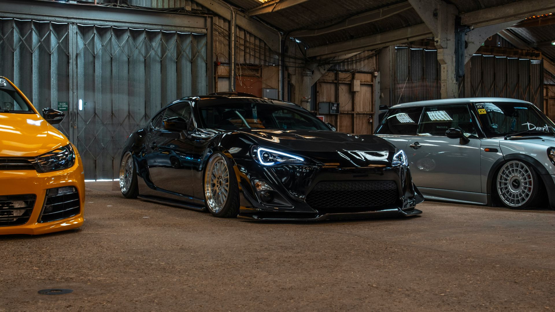 black coupe parked between two vehicles