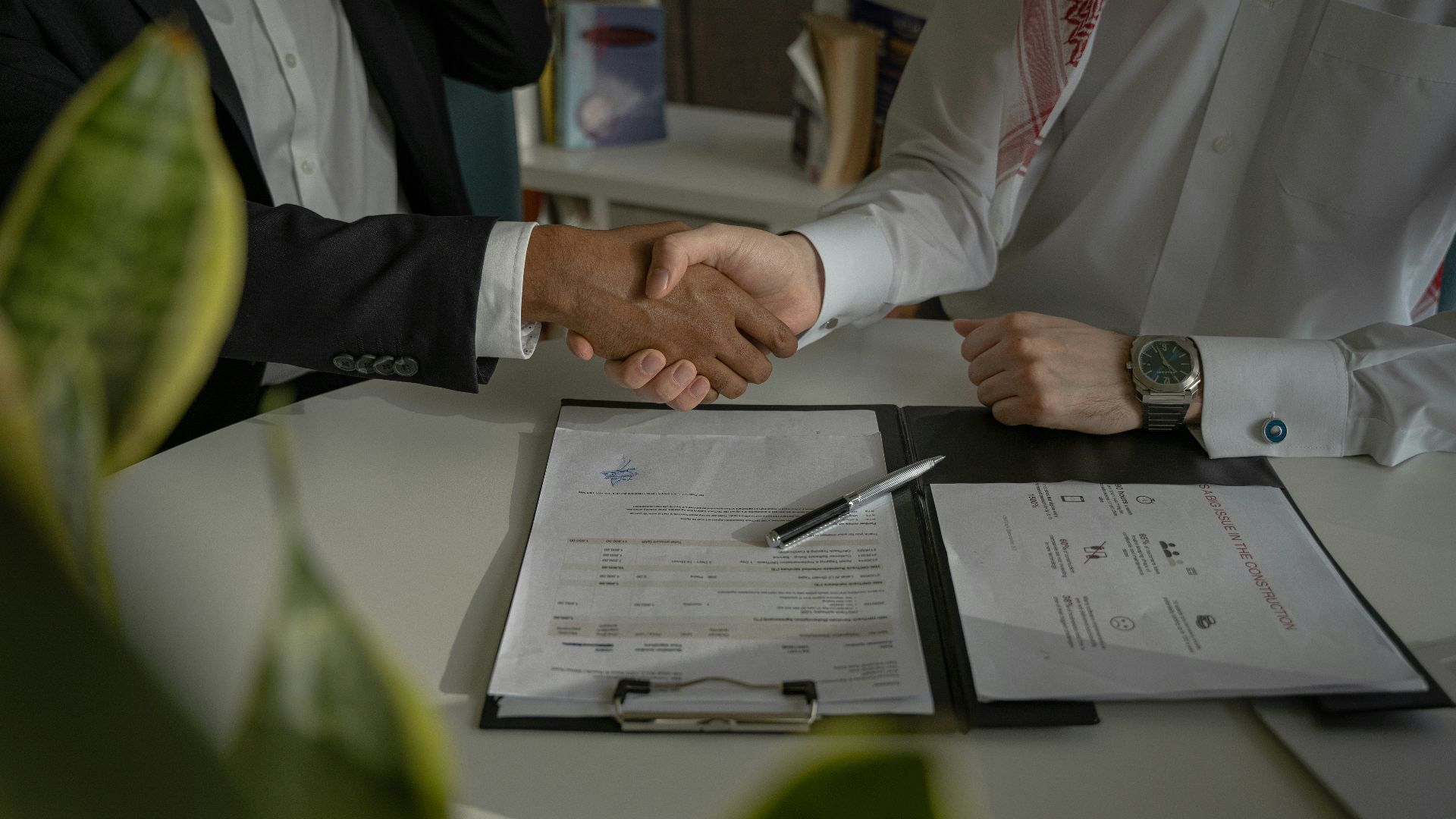 two people shaking hands over a piece of paper