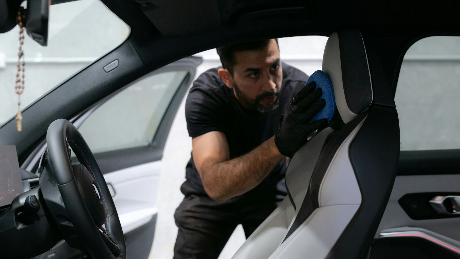 A man cleans a car seat inside the vehicle.