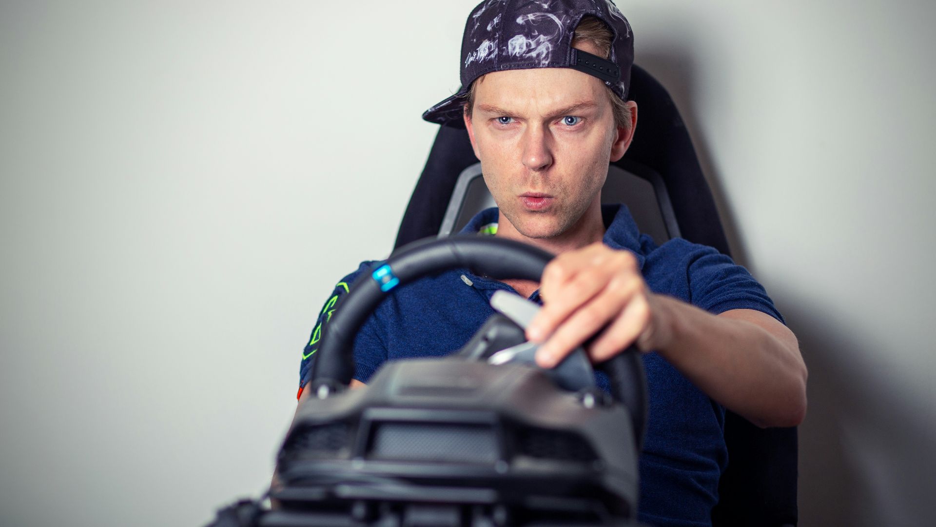 man in blue crew neck t-shirt wearing blue and white cap sitting on black office