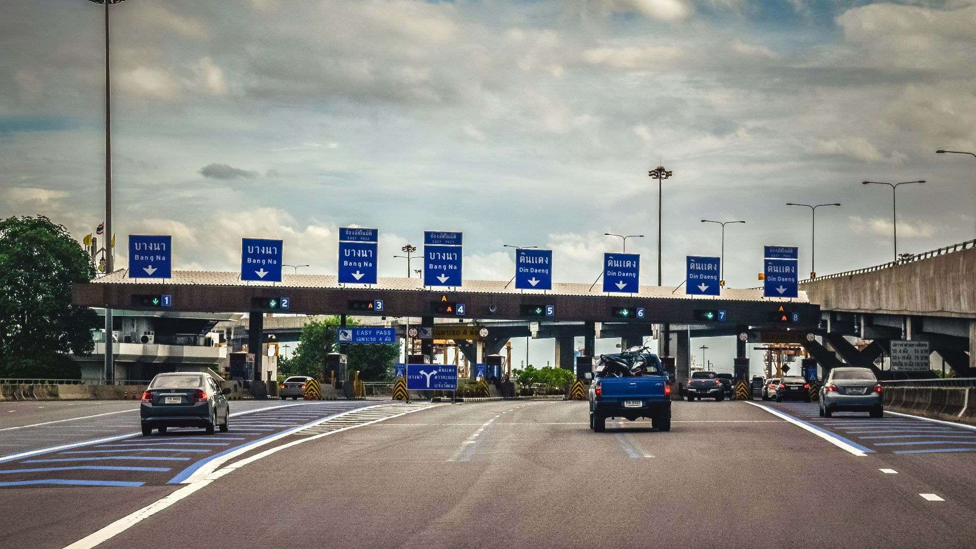 A blue truck driving down a highway under a cloudy sky