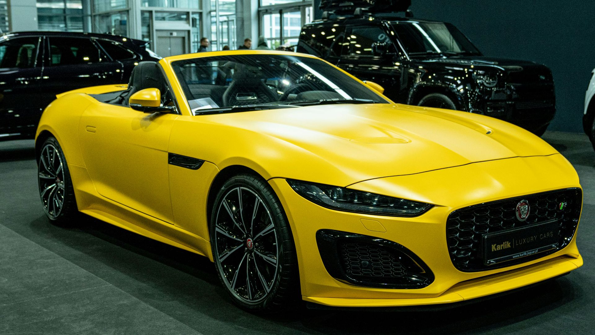 A yellow sports car in a showroom with other cars