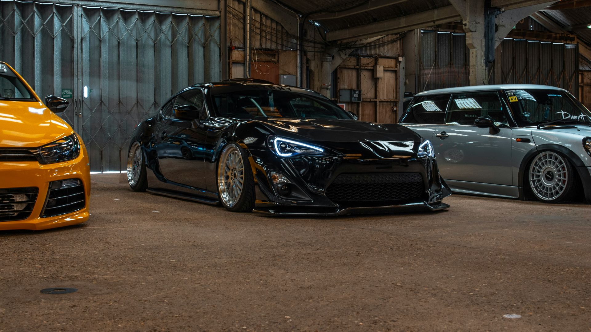black coupe parked between two vehicles