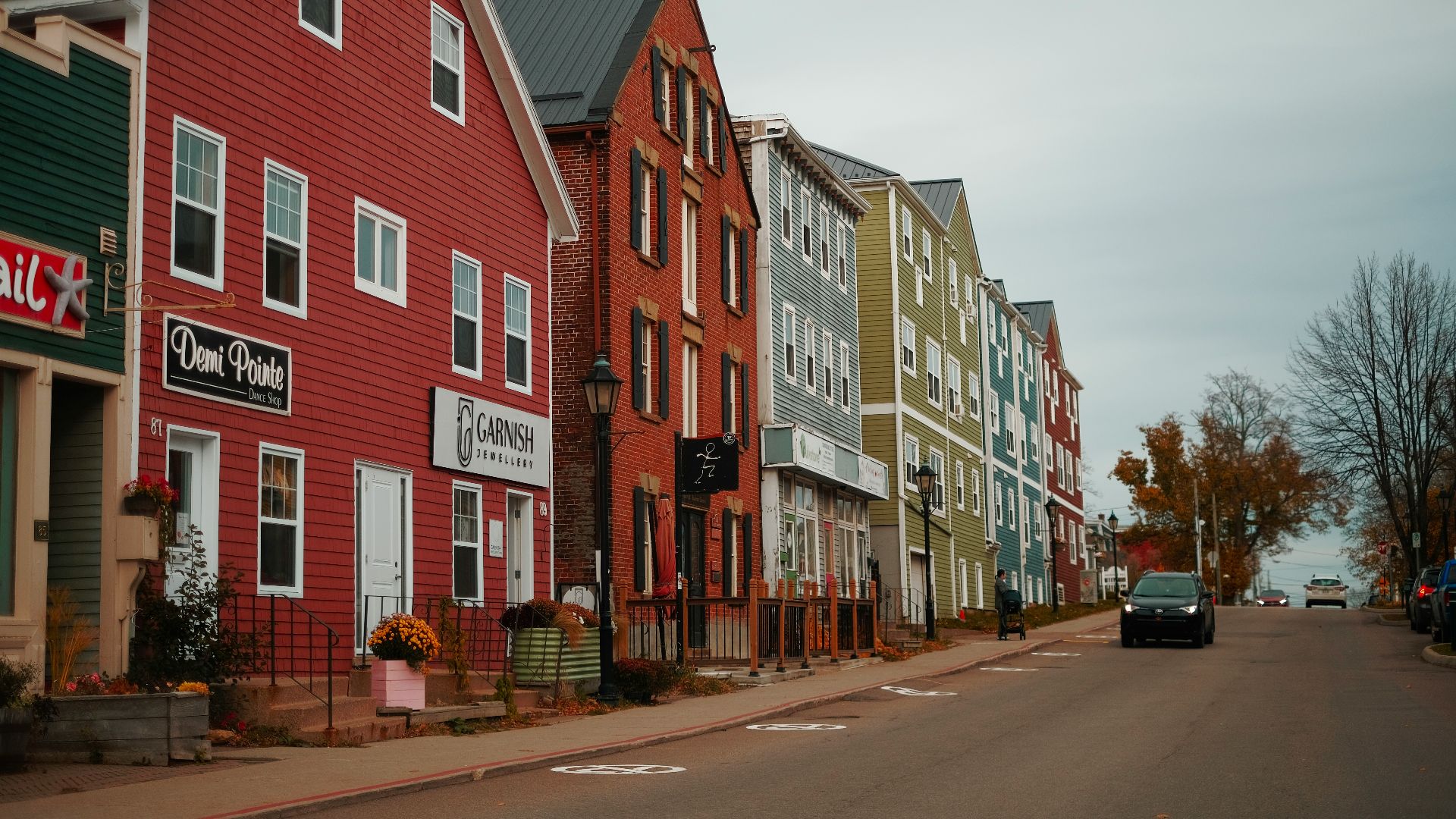 A row of houses on a street with a car parked on the side of the