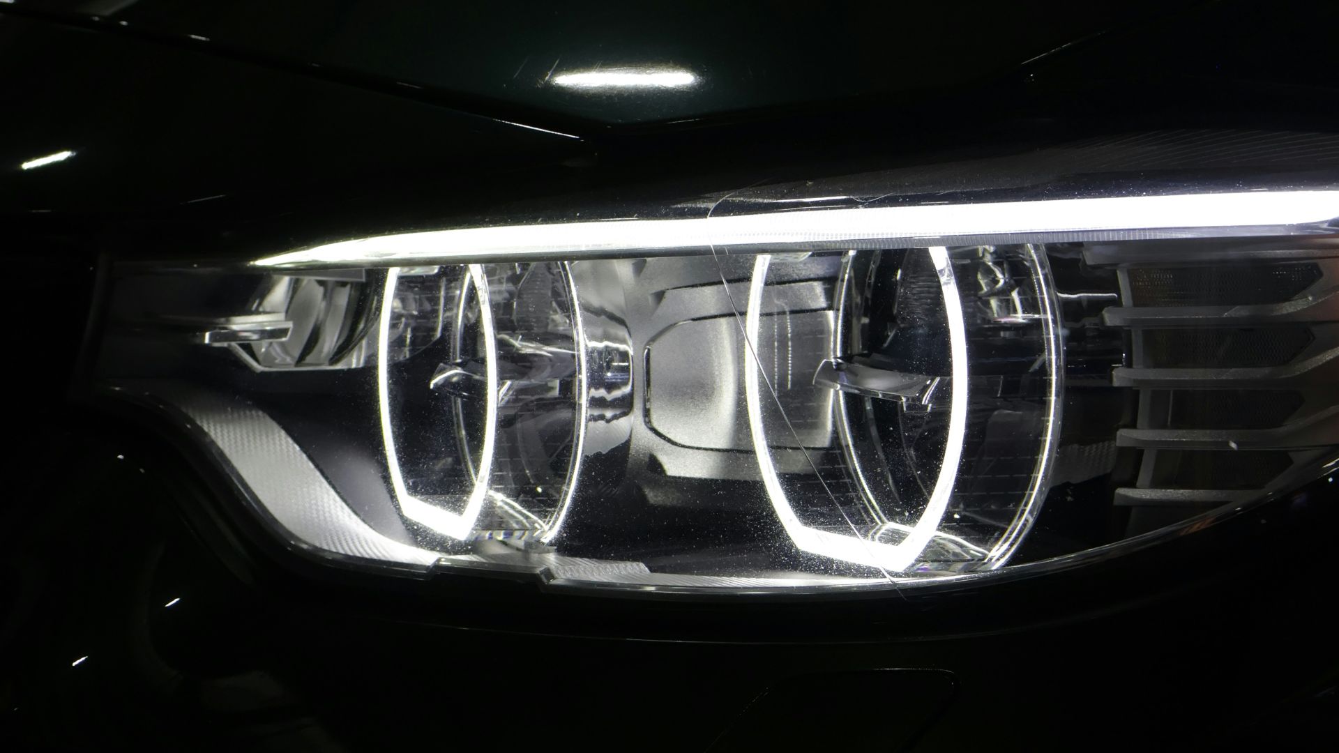 Close-up of a modern car headlight with glowing rings.
