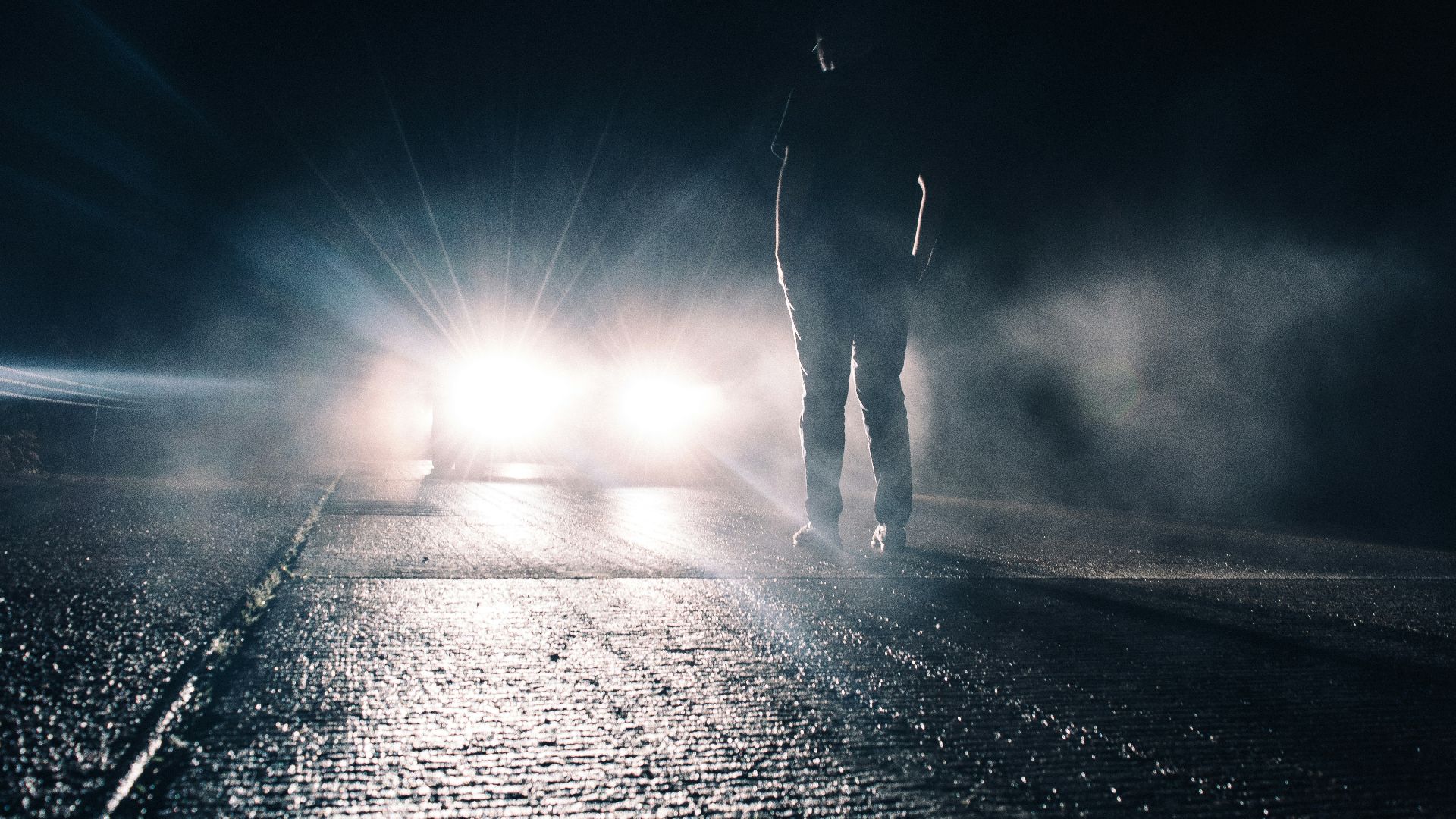 man standing in front of lighted car