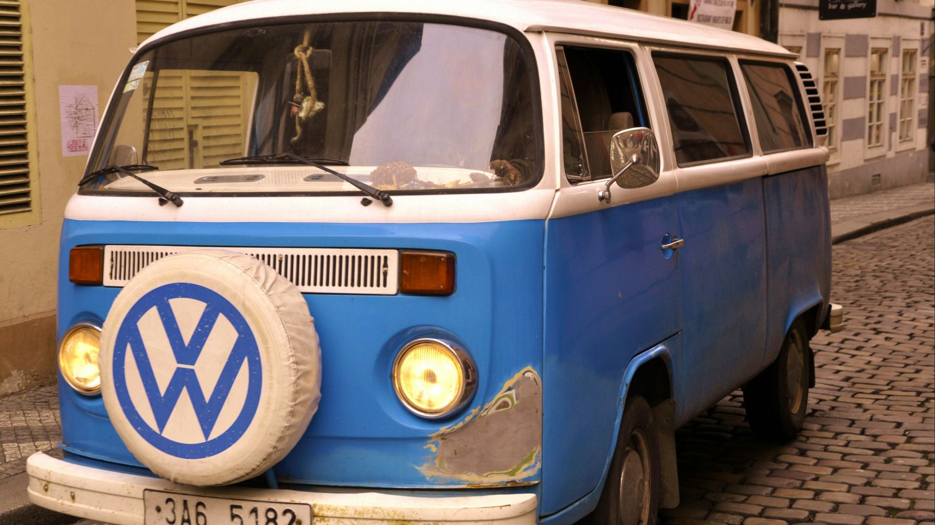 Blue and white volkswagen van parked on cobblestone street