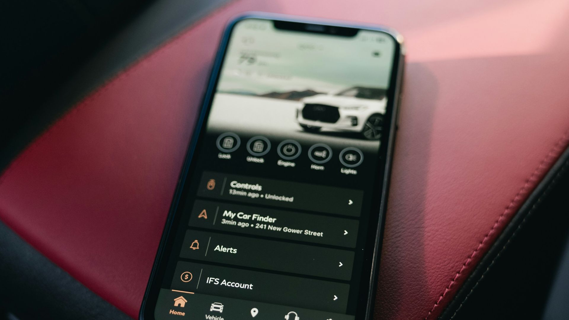 Smartphone resting on car's red and black leather seats.