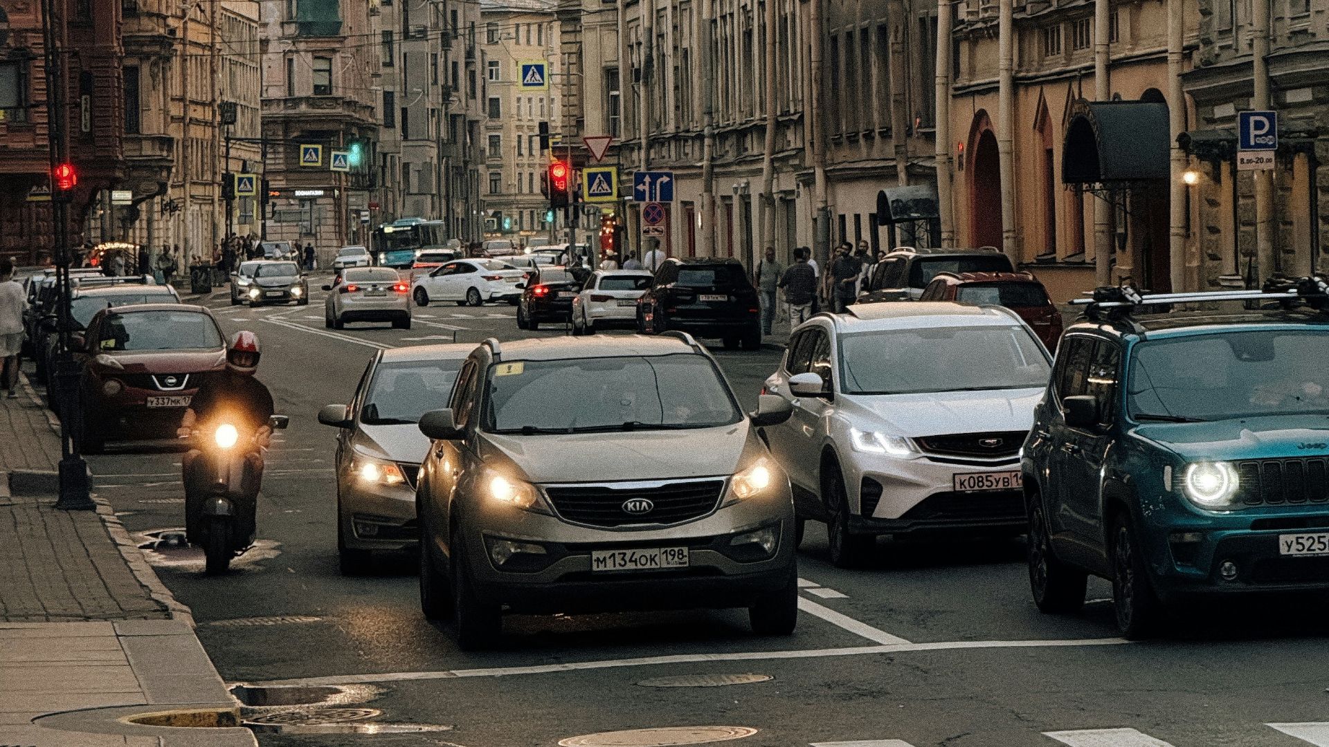Cars and motorcycle on city street at dusk